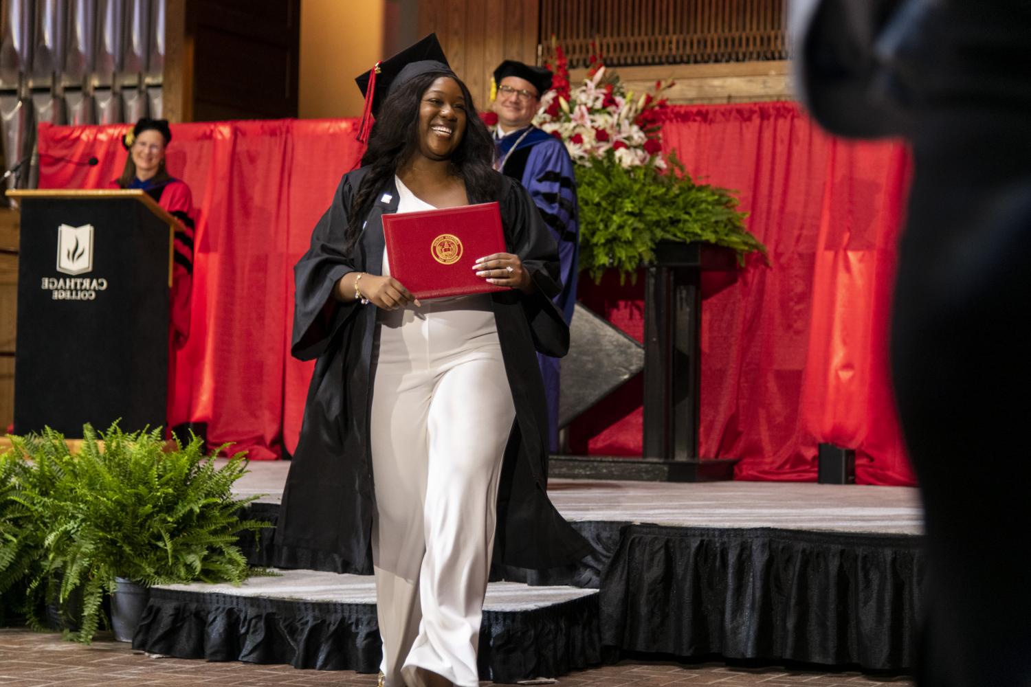 A 2023 <a href='http://72am.dhwee.com'>BETVLCTOR伟德登录</a> graduate beams as she leaves the Commencement stage after receiving her diploma from Carthage President John 吞下.